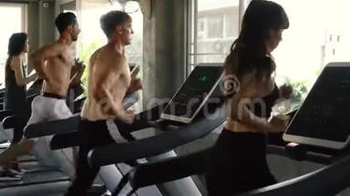 一群人在现代健身房的跑步机上锻炼。 健身男女一起工作